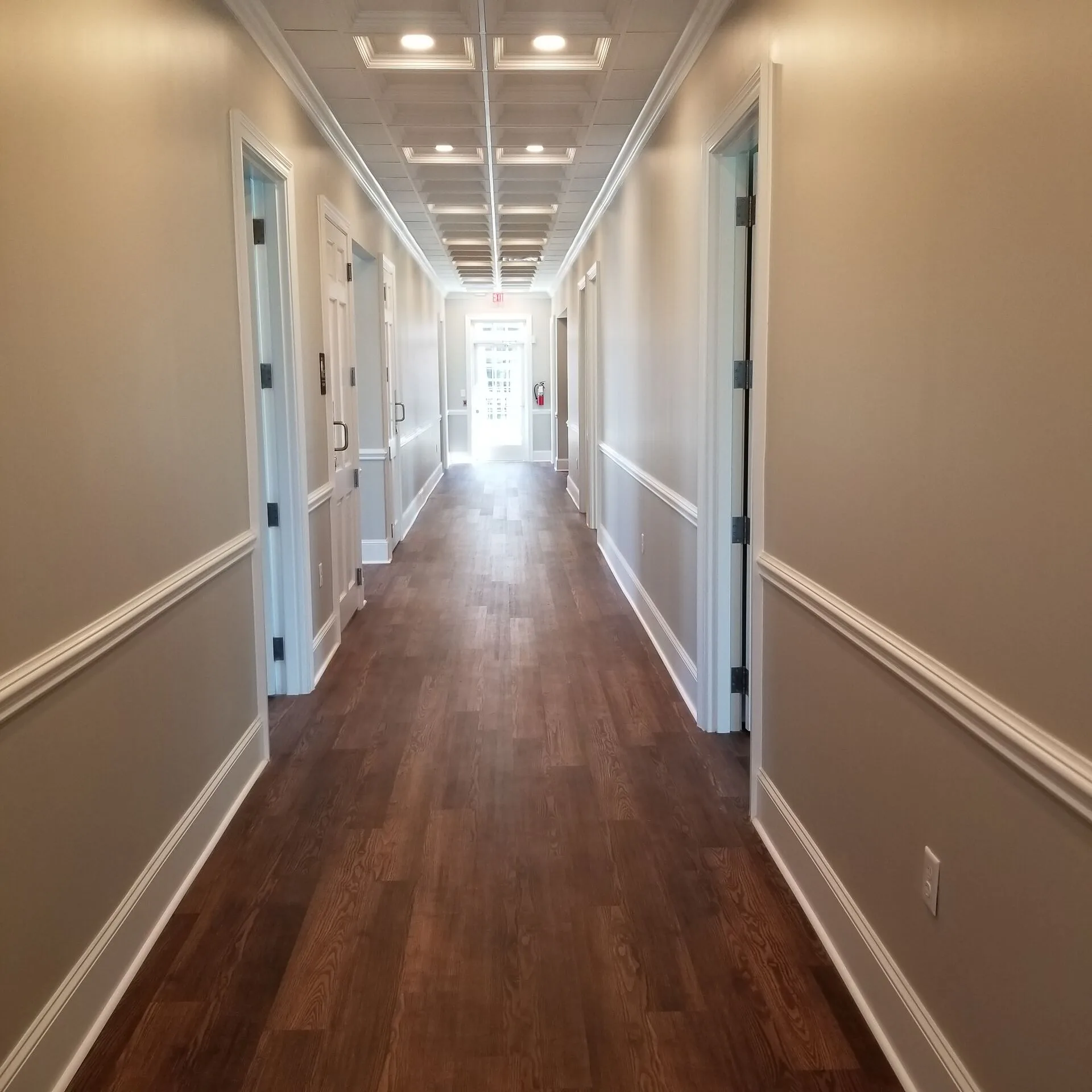 Traditional commercial office corridor with coffered ceiling and paneled wainscoting by PCS Builder