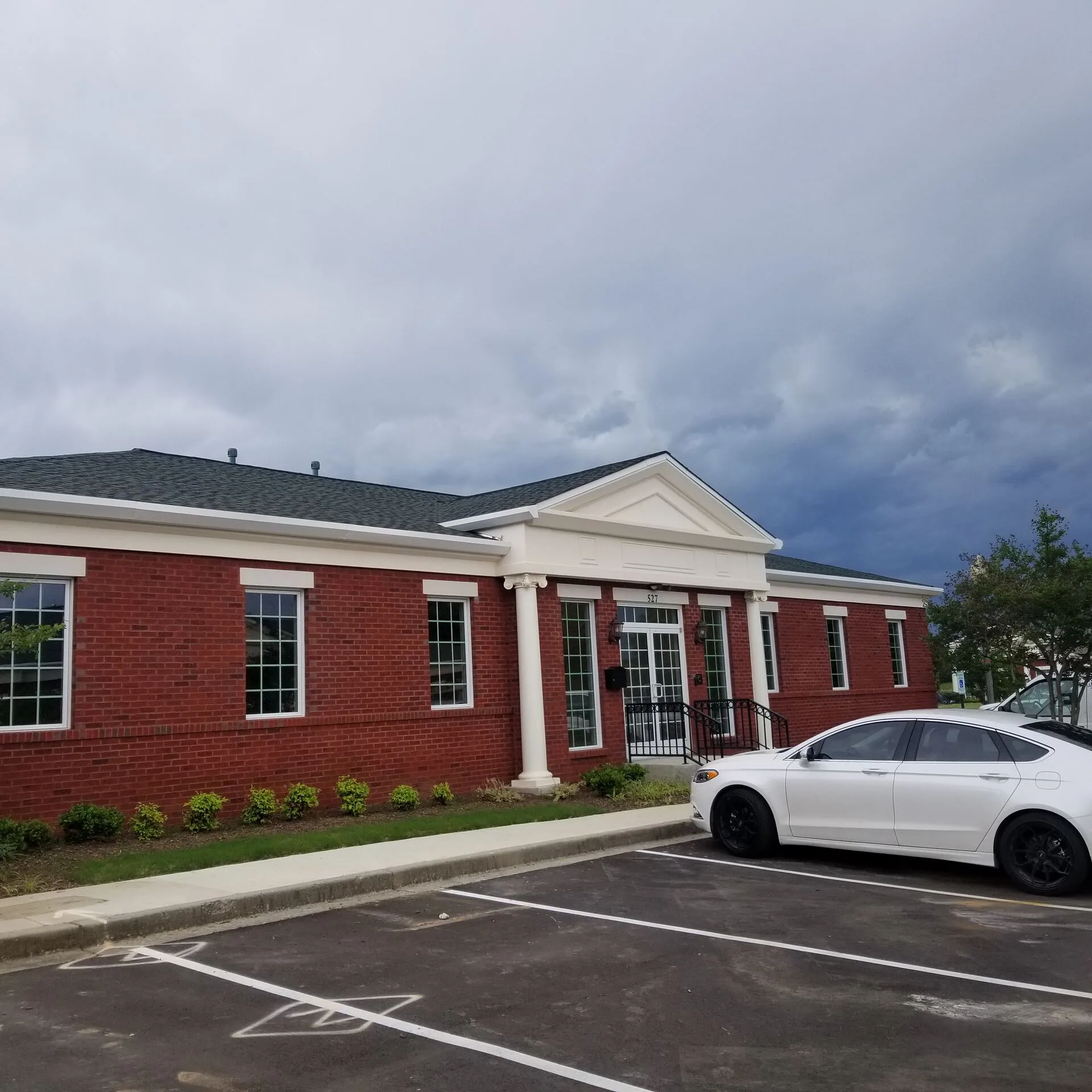 Red brick commercial building exterior with classical pedimented entry