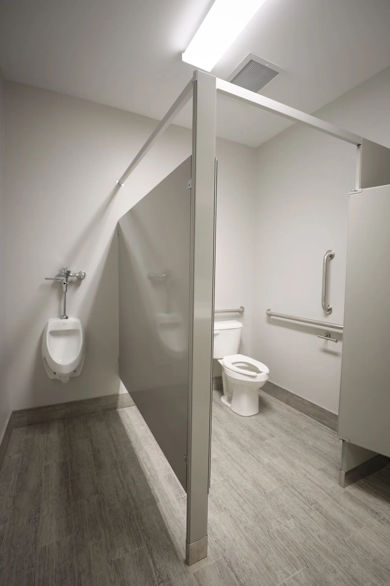 ADA-compliant restroom with urinal, toilet, and grab bars