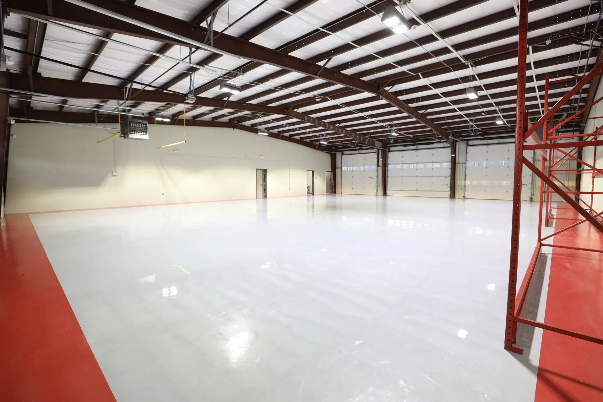 Warehouse interior with epoxy floor, red striping, and roll-up doors