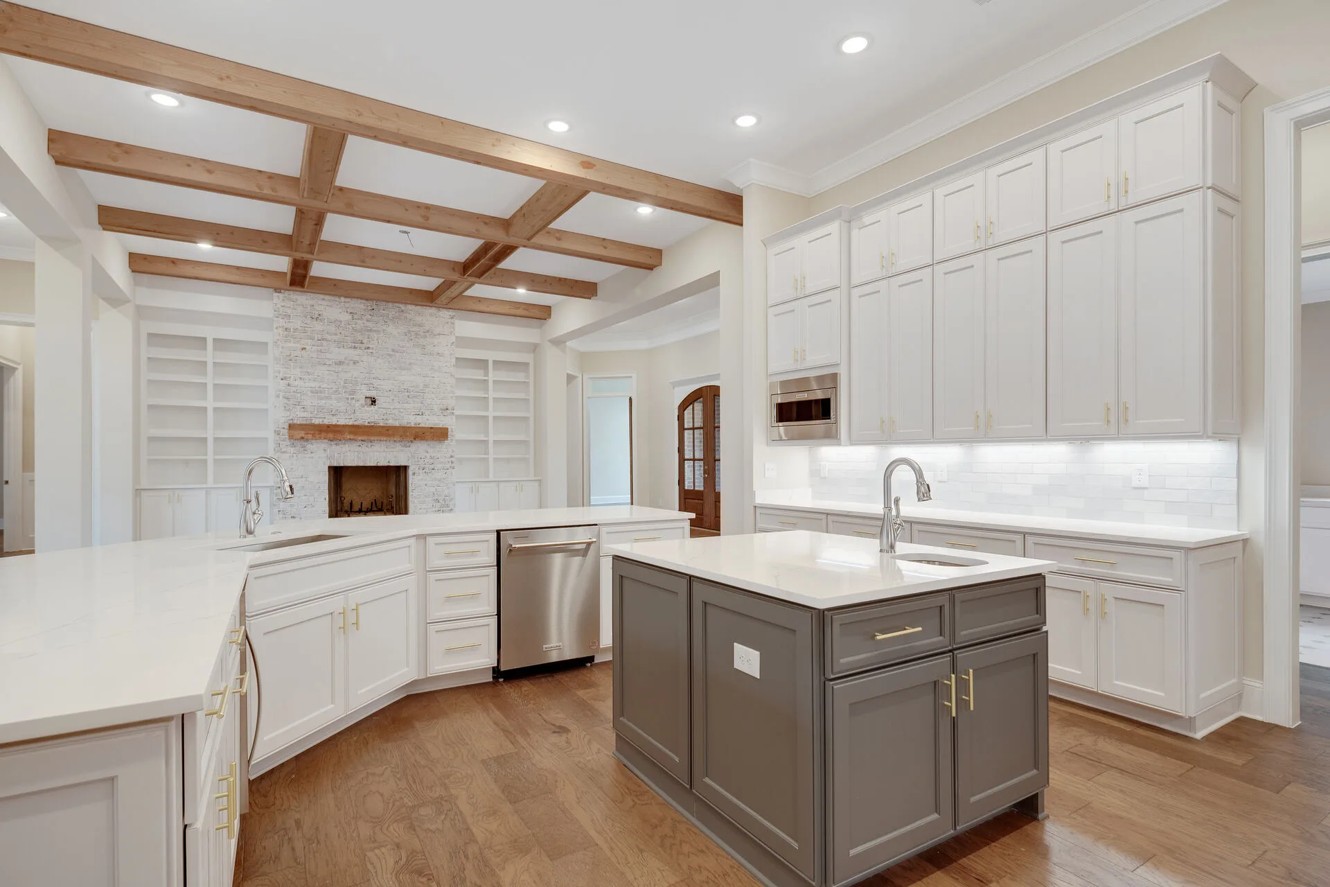 Custom gourmet kitchen with marble fireplace, coffered wood beam ceiling, and island