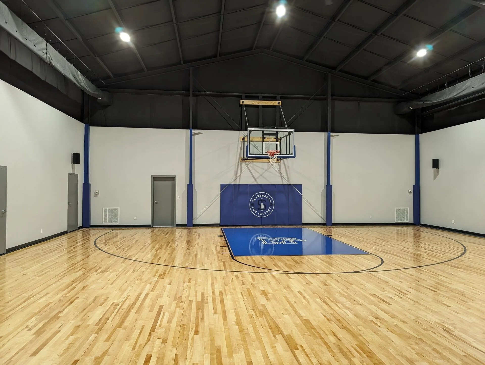 Private indoor basketball court with Scarbrough Fun Factory branded center wall pad and maple hardwood floor